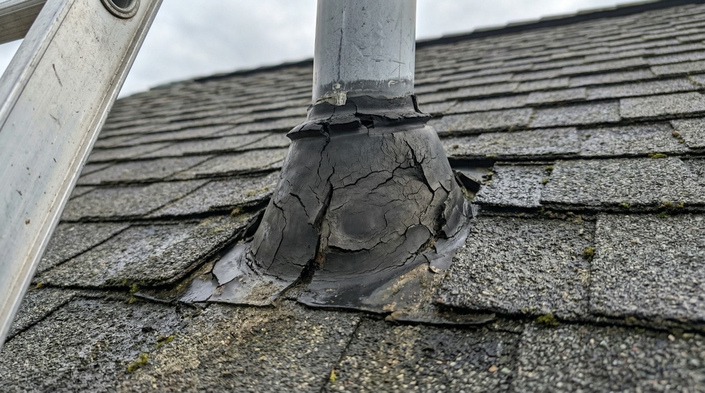 Cracked rubber boot on an asphalt shingle roof vent pipe